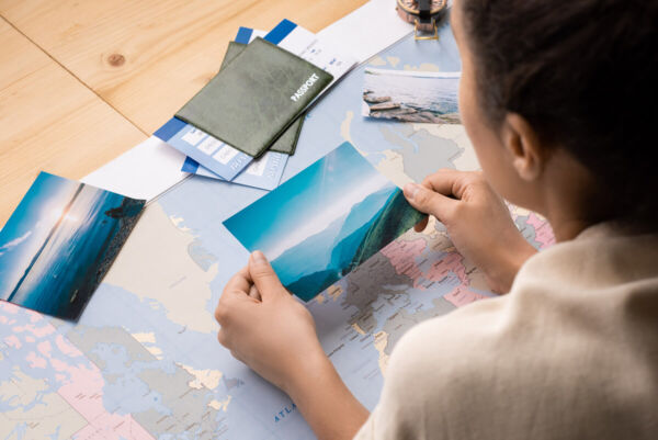 Photo shows a person looking at a photo of green mountains, a world map open in front of them.