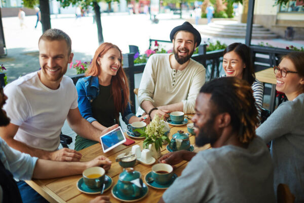 Photo of a mixed gender multiethnic group having a meal together at a cafe.j